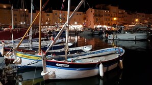 Un puerto deportivo con varias embarcaciones amarradas, rodeado de edificios con ventanas iluminadas.