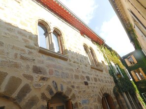 Un bâtiment en pierre doté de fenêtres en arc de cercle et d’un toit recouvert de tuiles rouges.