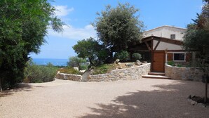 A stone-walled property with a wooden door and steps leading to a covered porch. - Brand new villa with secured pool, panoramic view of sea and mountain, quiet (Zonza)