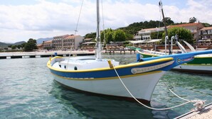 A boat docked at a marina with clear water, a dock, and buildings in the background. - Brand new villa with secured pool, panoramic view of sea and mountain, quiet (Zonza)