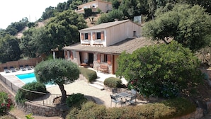 A villa with a swimming pool, outdoor seating, and a stone wall surrounding the property. - Brand new villa with secured pool, panoramic view of sea and mountain, quiet (Zonza)