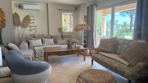 A living room with a sofa, armchair, coffee table, and wicker ottoman. - *NEWS *Charming zen villa, luxury, quiet, view availability in August contact me (Pont-Saint-Esprit)