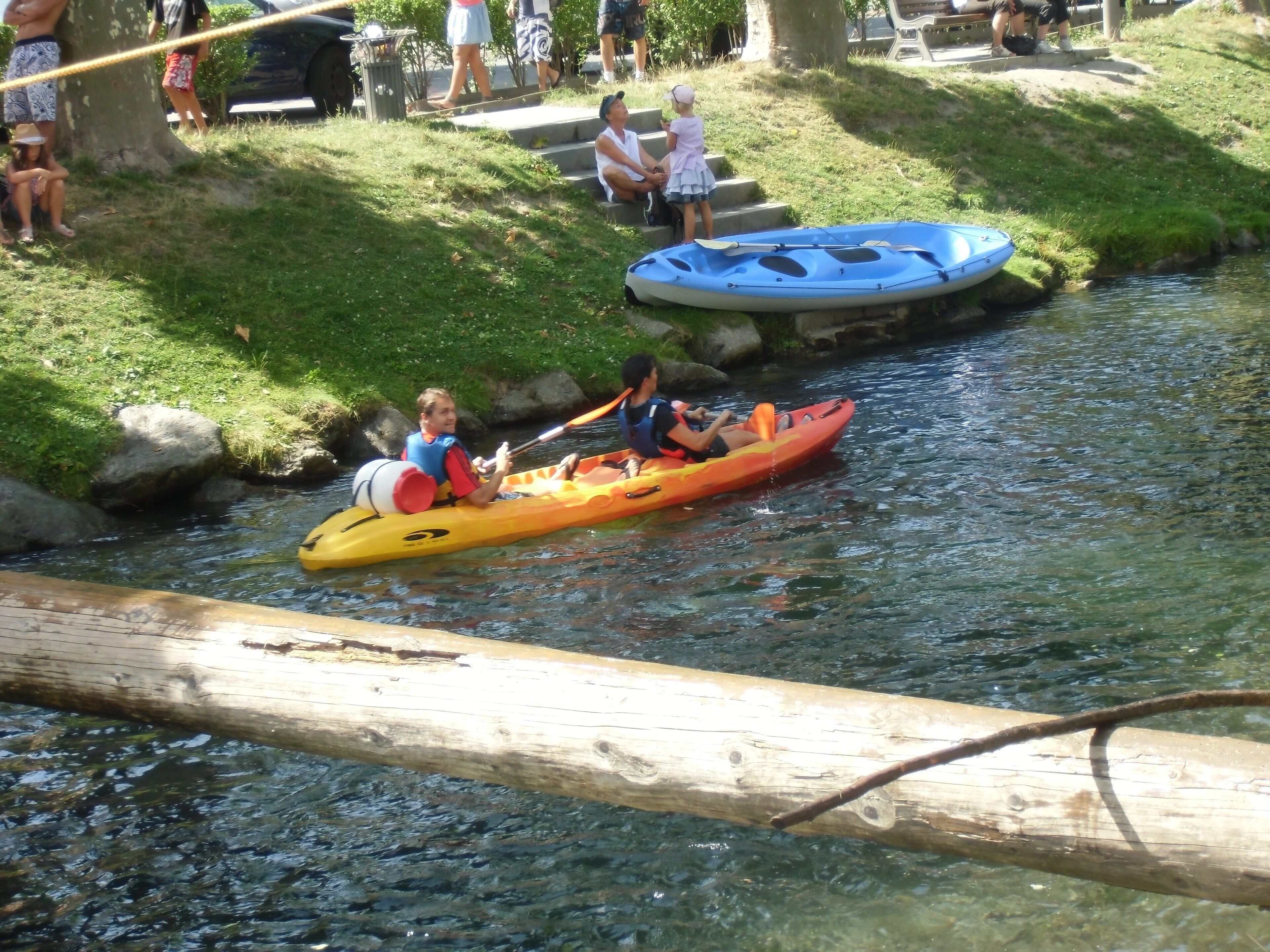 Ein Fluss mit Kajaks und einem Treibholz im Wasser.