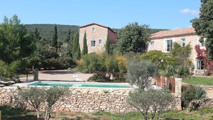 A stone building with a swimming pool, surrounded by trees and a stone wall. - Gite with a high standard of comfort between the garrigue and the provence (Argelliers)