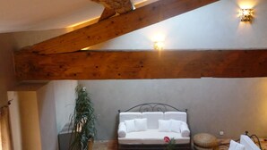 A cozy indoor patio with a white sofa, wicker chairs, and a small table. - Gite with a high standard of comfort between the garrigue and the provence (Argelliers)