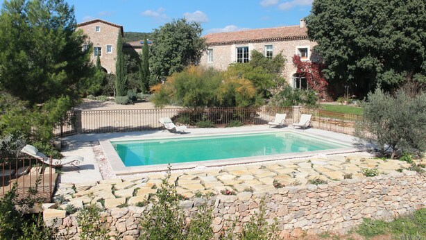 A stone building with a swimming pool, surrounded by trees and a stone wall. - Gite with a high standard of comfort between the garrigue and the provence (Argelliers)