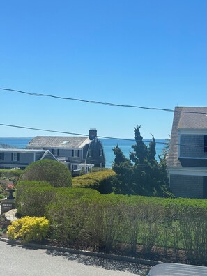 Una zona residencial costera con casas, un cielo azul despejado y el océano al fondo.