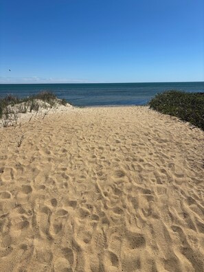 En sandstrand med klar himmel och stilla hav.