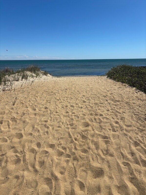 Una playa arenosa con cielo despejado y mar tranquilo.