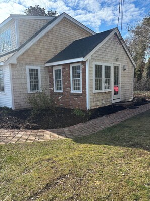A two-story house with a brick facade, a covered porch, and a landscaped yard.