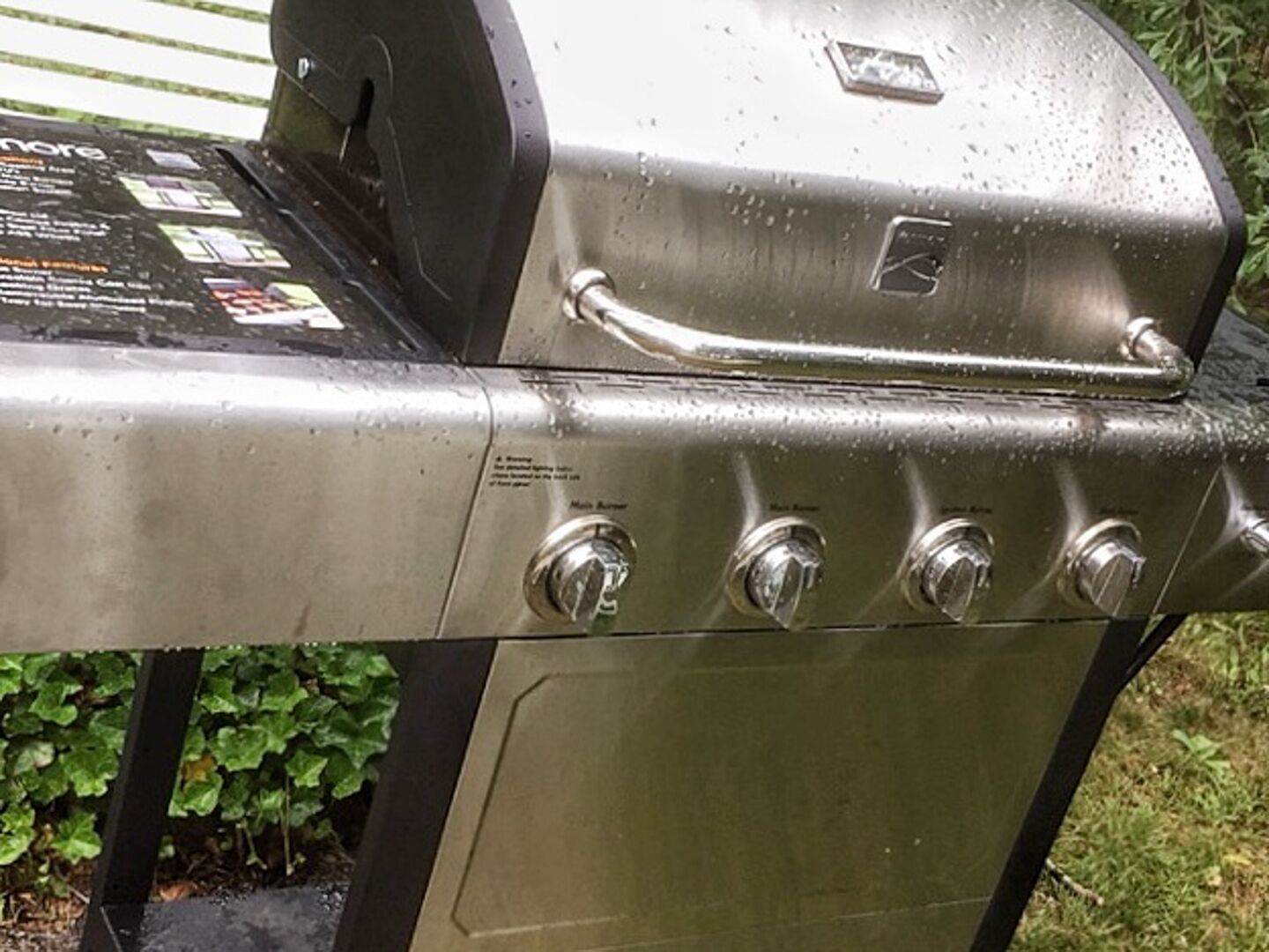 A stainless steel barbecue grill with a digital display and four control knobs.