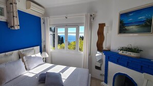 Ein Schlafzimmer mit Bett, Fenster mit Ausblick, einem Gemälde und einem Kamin.