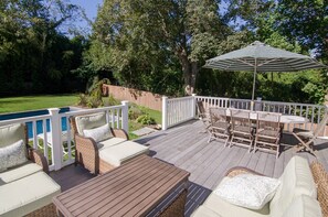 A deck with outdoor furniture, a pool, and a wooden fence. - Brand New in the Heart of East Hampton Village with Pool (East Hampton)