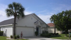 A single-story house with a white exterior, a garage, and a well-maintained lawn. - Beachwalk Isles Executive 4 Bedroom Lakeside Pool Villa (Ft Myers)