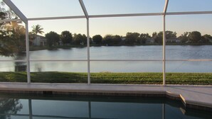A pool with a view of a lake and houses in the background. - Beachwalk Isles Executive 4 Bedroom Lakeside Pool Villa (Ft Myers)