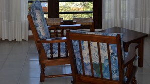 Habitación con una mesa de madera y dos sillas, vista al mar y un balcón con barandilla.