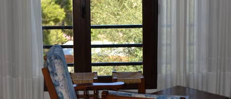 Habitación con una mesa de madera y dos sillas, vista al mar y un balcón con barandilla.