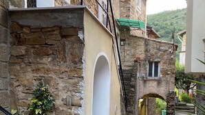 A narrow stone pathway leading to a building with a stone facade and a small archway. - Beautiful farm house with pool, open spaces  and amazing sea views  (Bordighera)