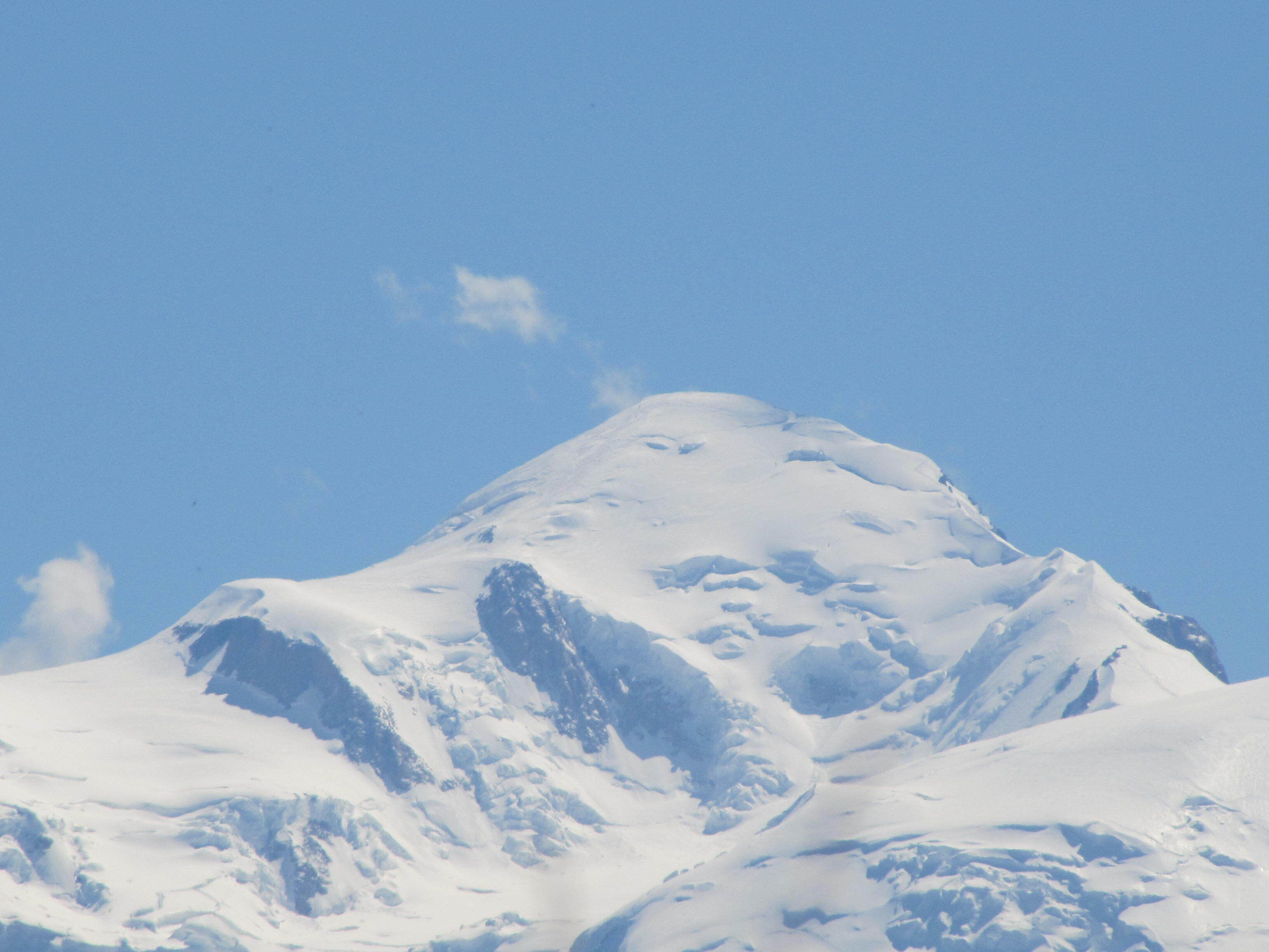 Een bergtop bedekt met sneeuw onder een heldere lucht.