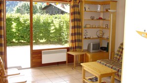 Ein gemütliches Wohnzimmer mit einem Holztisch, einer Couch, einem Fernseher und einem Bücherregal.