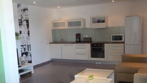 A modern kitchen with white cabinets, a microwave, and a coffee maker. There is a white table with a green candle in the foreground. - Apartment/ flat - Sari SolenzaraHouse with character (Sari-Solenzara)