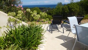 An outdoor patio with two chairs and a table, overlooking a scenic view of the ocean and lush greenery. - Apartment/ flat - Sari SolenzaraHouse with character (Sari-Solenzara)