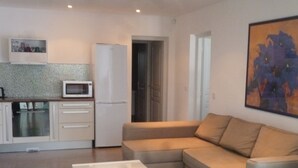 A modern living room with a beige sofa, a white coffee table, and a kitchen area with a microwave, oven, and refrigerator. - Apartment/ flat - Sari SolenzaraHouse with character (Sari-Solenzara)