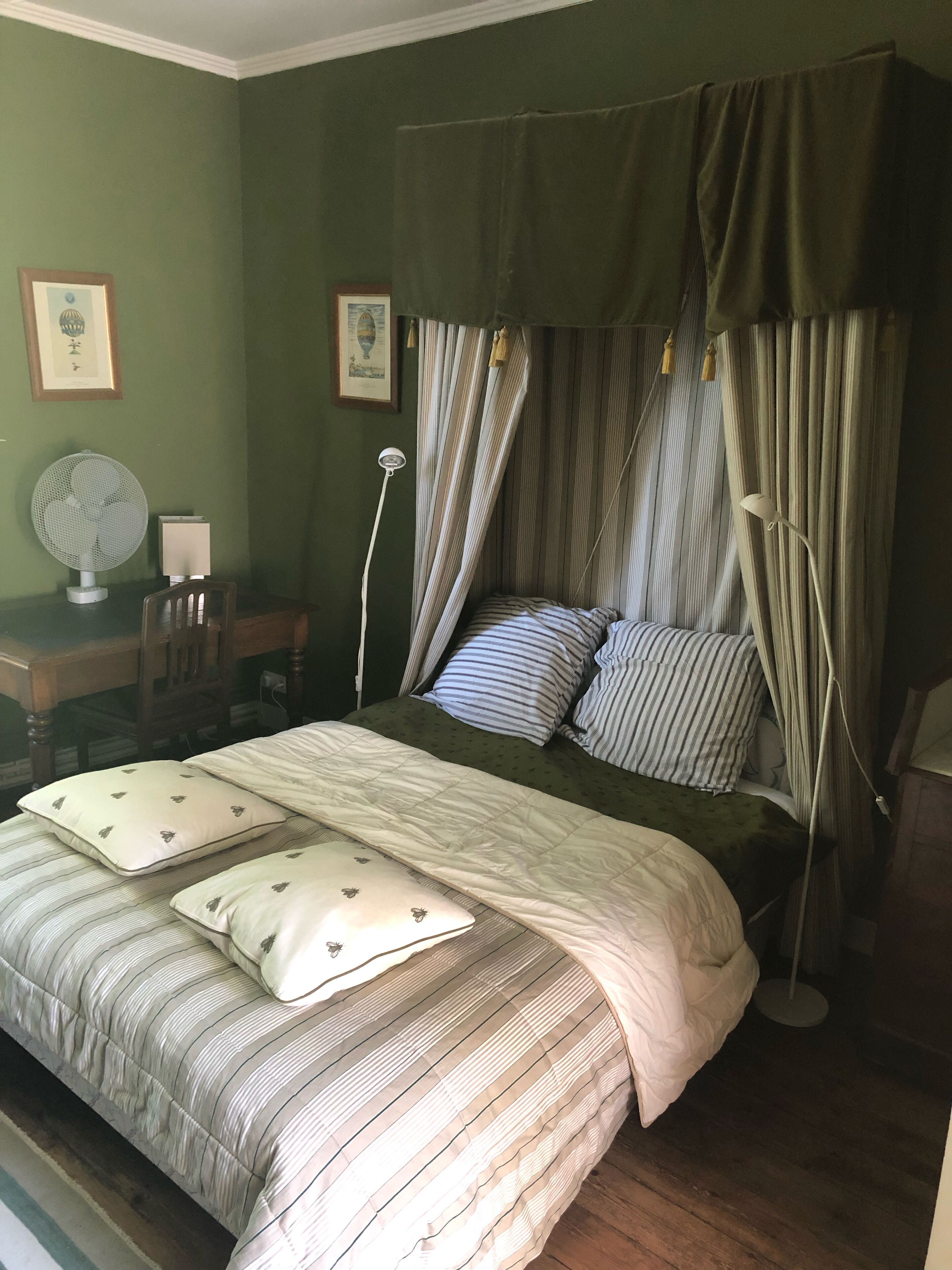Une chambre à coucher comprenant un lit, un bureau, une chaise et un lampadaire.