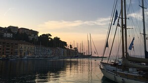 A marina with boats docked, buildings along the waterfront, and a clear sky.