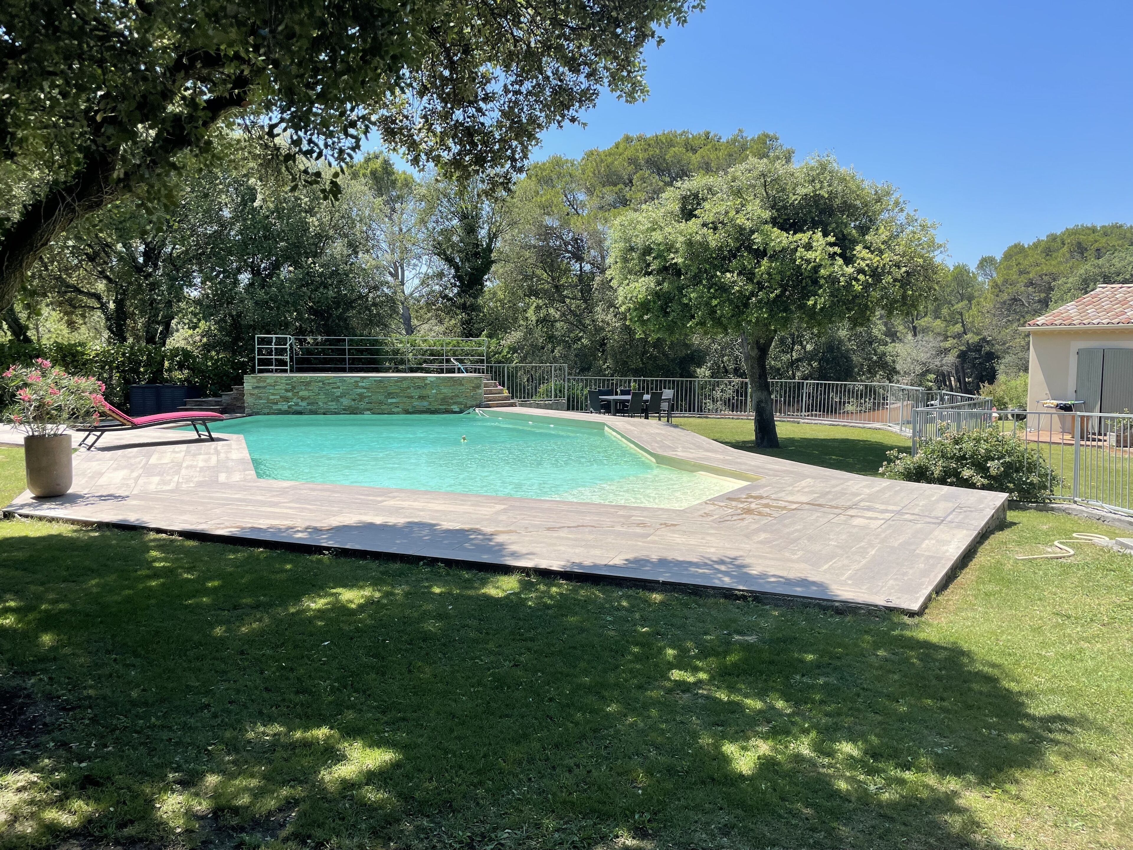 A backyard with a swimming pool, a patio area, and a lawn.