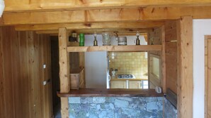 Eine Holzküche mit Stein Arbeitsplatten, Holzschränken und einer gefliesten Spritzschutzwand.