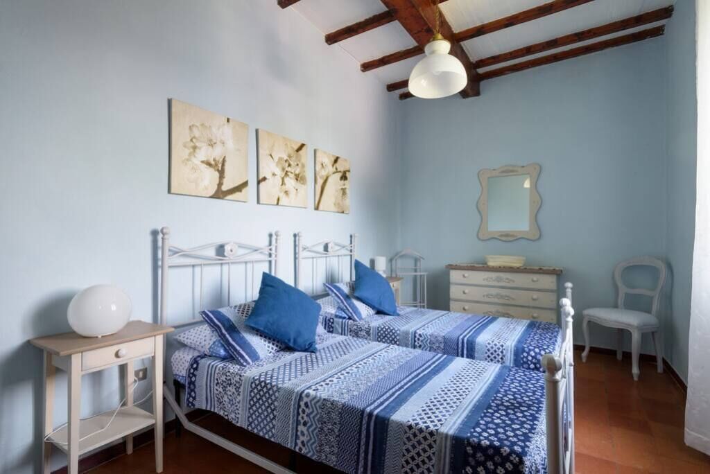 Un dormitorio con dos camas, una mesita de noche, un aparador, una silla y decoración en la pared.