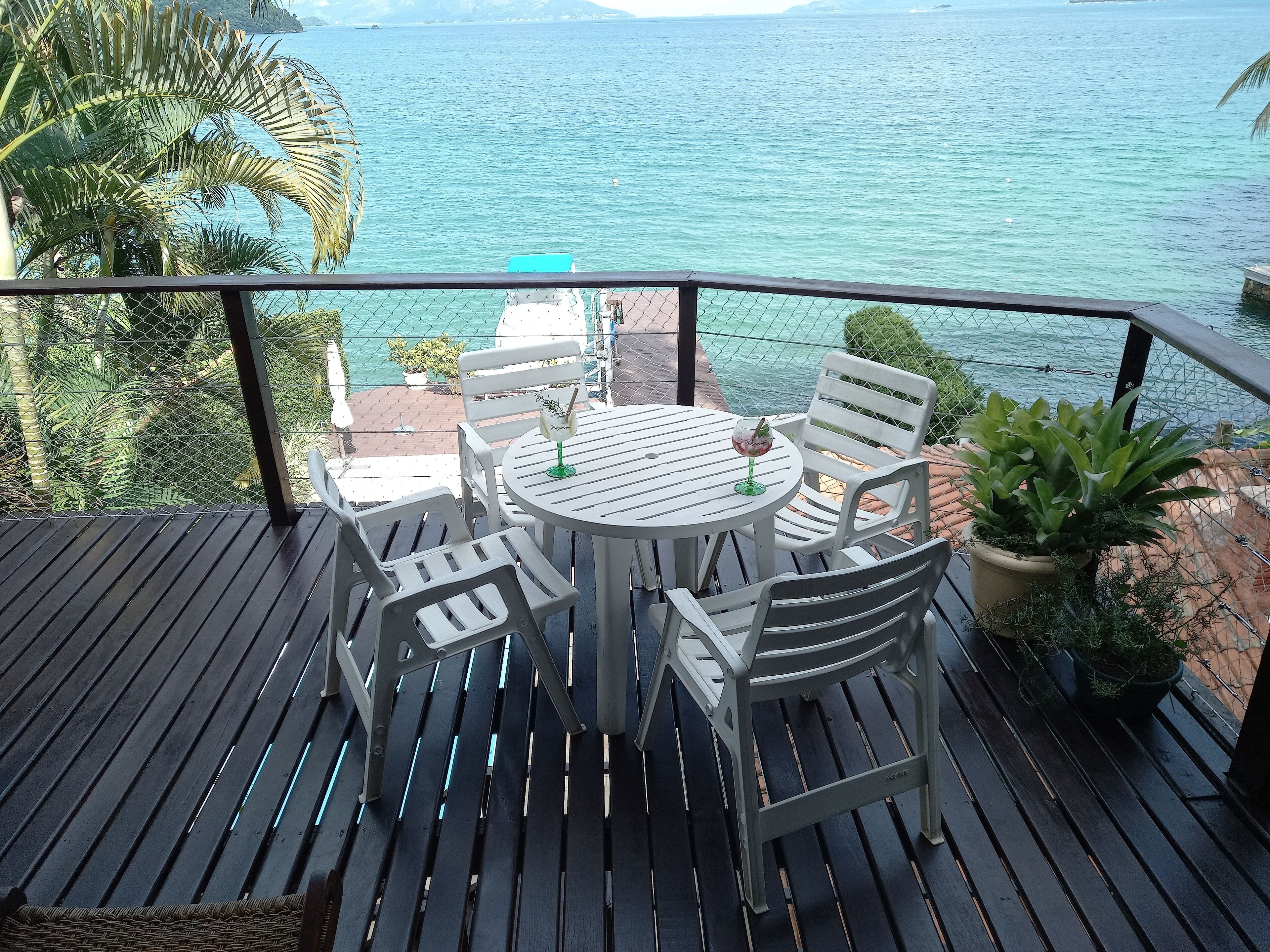 A deck with a table and chairs overlooking a body of water.
