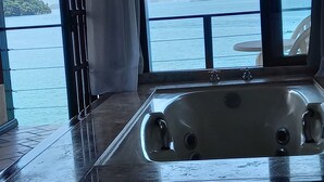 A bathroom with a large bathtub, a window with a view of the sea, and a curtain. - Wonderful house by the water in Angra dos Reis. (Angra dos Reis)