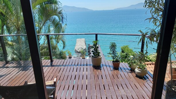 A wooden deck with potted plants and a view of the sea. - Wonderful house by the water in Angra dos Reis. (Angra dos Reis)