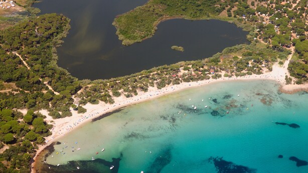 Eine Luftaufnahme einer Küstenlandschaft mit Strand, Booten und einer kleinen Insel.