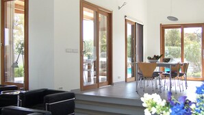 Eine moderne Küche mit Essbereich, ausgestattet mit einem großen Fenster, einem Esstisch mit Stühlen und einem schwarzen Sofa.