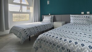 Een slaapkamer met twee bedden, een raam met uitzicht en een wand in teal blauw.