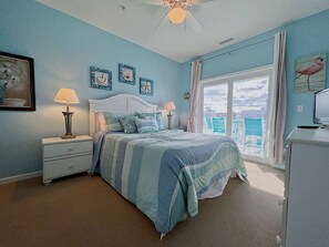 Un dormitorio con cama, mesitas de noche, un escritorio y un ventanal con vistas.