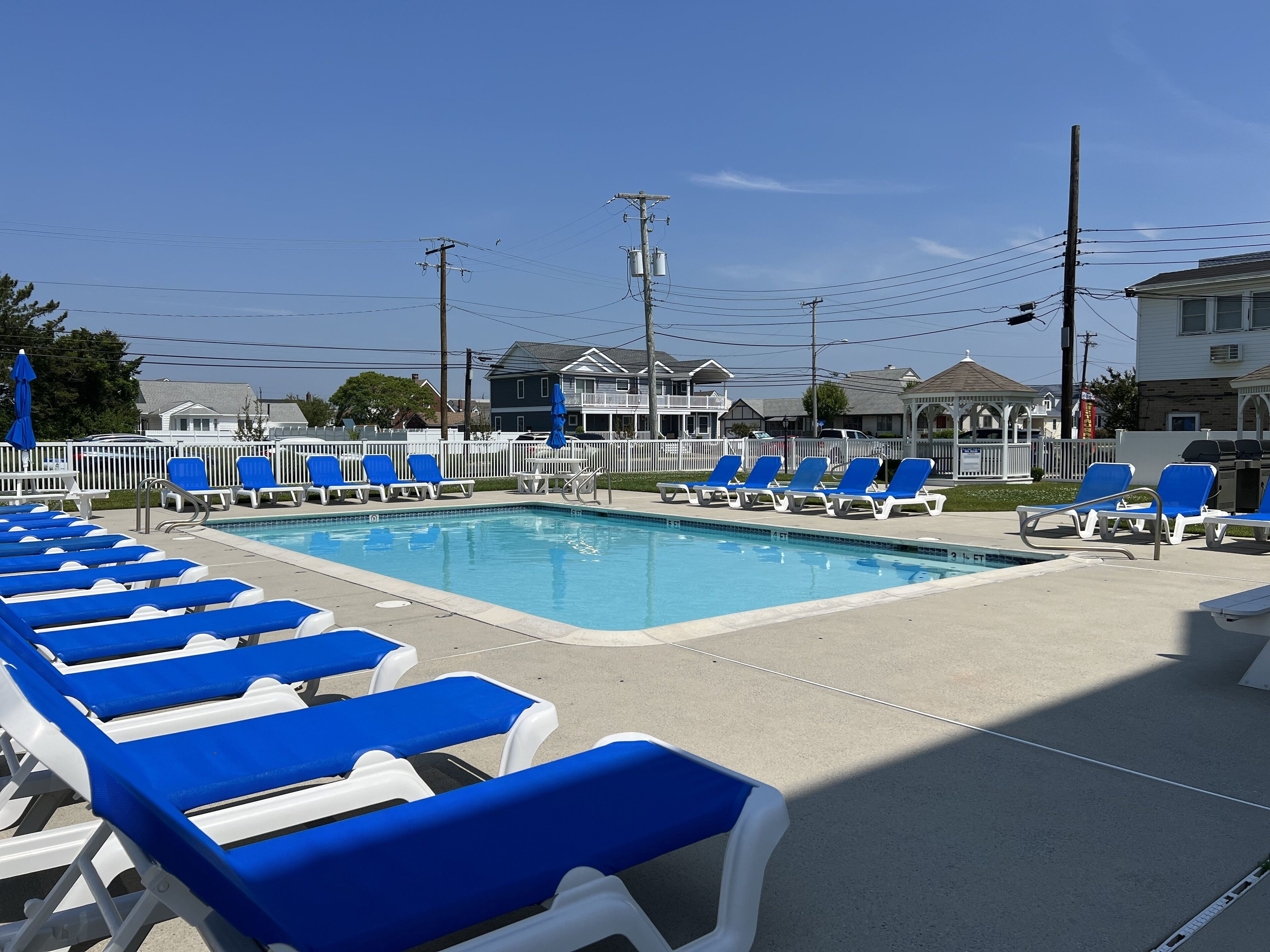 Una piscina con sillones de descanso azules y blancos alrededor.