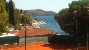 Un court de tennis offrant une vue sur une plage et des montagnes.