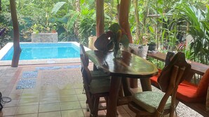 A covered outdoor dining area with a pool in the background. - Casa Del Caribe with Bali Style Pool for Rent in Cocles, 300 meters from beach (Cocles)