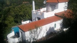 A white building with a red roof, a satellite dish, and a swimming pool.