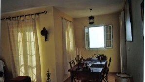 A dining area with a table and chairs, a window with curtains, and a hanging light fixture.