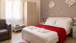 A modern bedroom with a bed, a nightstand, a chair, and a wardrobe. - John Akroyiali rooms (Sfakia)