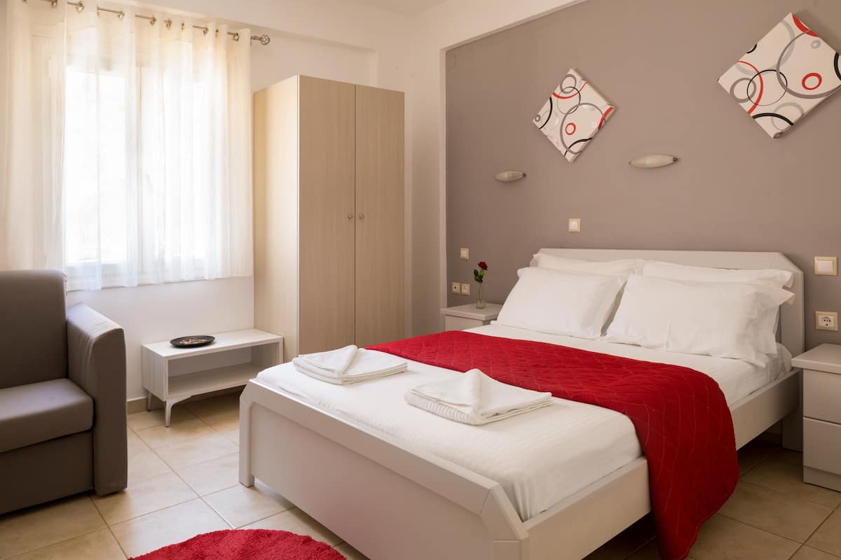 A modern bedroom with a bed, a nightstand, a chair, and a wardrobe.