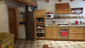A kitchen with wooden cabinets, a refrigerator, a microwave, and a tiled floor. - Perfect  location quiet surroundings  spacious comfortable & functional  (Brides-Les-Bains)