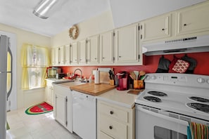 A kitchen with white cabinets, a stove, and a sink.