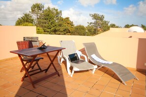 Eine Terrasse im Freien mit einem Tisch, zwei Stühlen und einem Laptop.