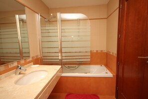 Ein Badezimmer mit Waschbecken, Spiegel, Dusche und Badewanne.